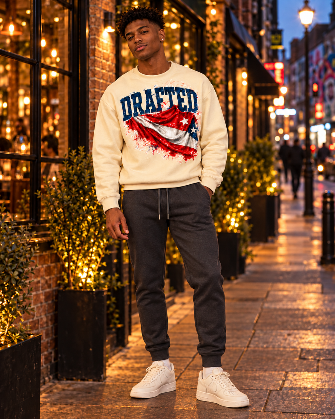 Young adult AI model wearing the cream Drafted flag sweatshirt and charcoal joggers in East London