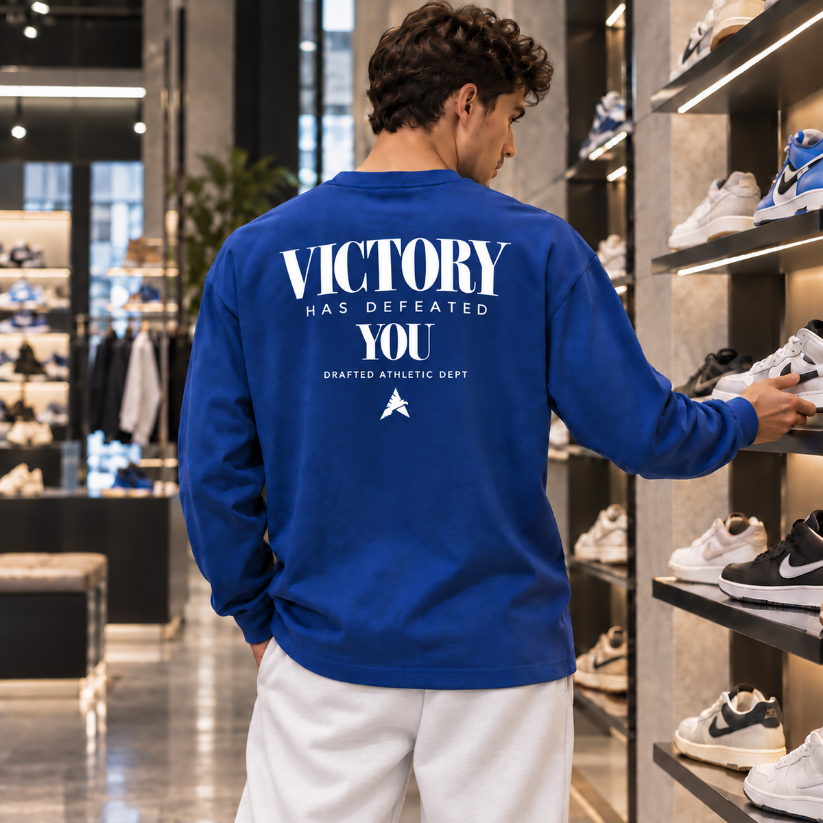 Royal blue Victory back print in a London sneaker store with white relaxed sweatpants