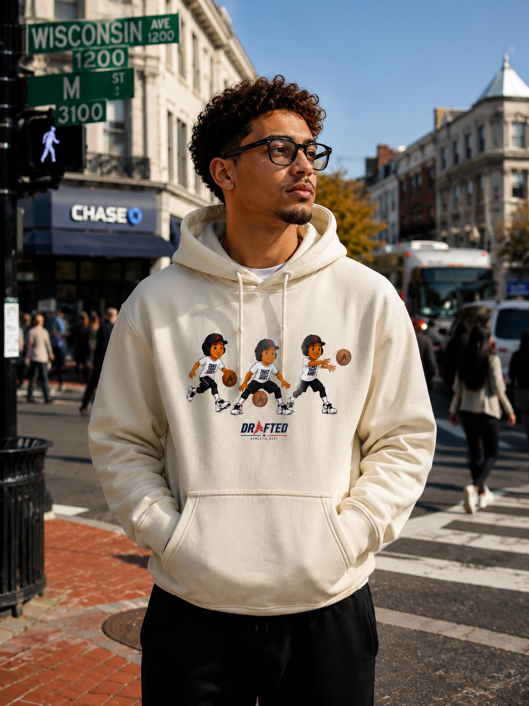 Model wearing the cream Triple Threat Cartoon Hoodie on a city street